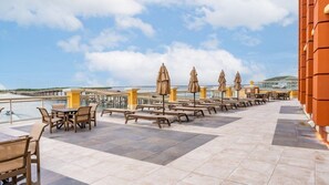 A terrace with outdoor seating and a view of the sea.