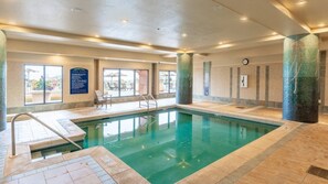 Una piscina interior con paredes de vidrio transparente, piso de baldosas y un cartel que indica ‘no buceo’.