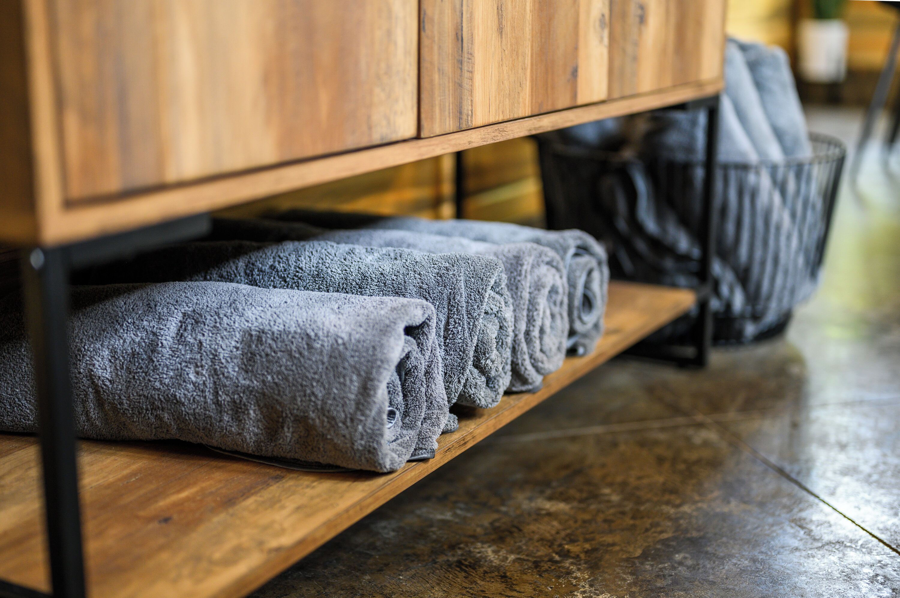 A wooden shelf with neatly folded gray towels.