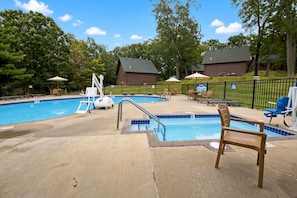 Ein Schwimmbecken mit Sprungbrett, Liegestühlen und einer kleinen Liegefläche.