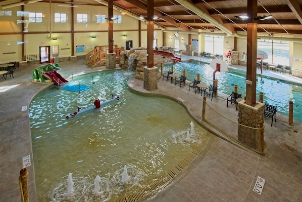 An indoor swimming pool with multiple lanes, a slide, and a waterfall feature.