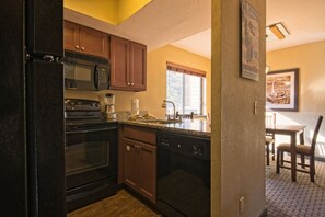 A compact kitchen with a refrigerator, microwave, stove, and dishwasher.