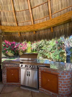 An outdoor kitchen with a grill, built-in oven, and a brick surround.