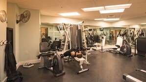 Un gimnasio con equipo de ejercicio diverso, incluyendo cintas de correr, bicicletas estáticas y máquinas de pesas.