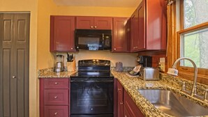 Cocina con encimera de granito, pileta de acero inoxidable y muebles colorados.