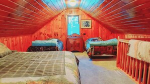 Une chambre mansardée avec deux lits, un plafond en bois et une fenêtre donnant sur un paysage agréable.