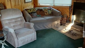 Un salon chaleureux avec un grand canapé, un fauteuil confortable et une cheminée.