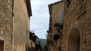 Une ruelle étroite pavée, bordée de bâtiments en pierre dotés de portes et de fenêtres en arc de cercle.