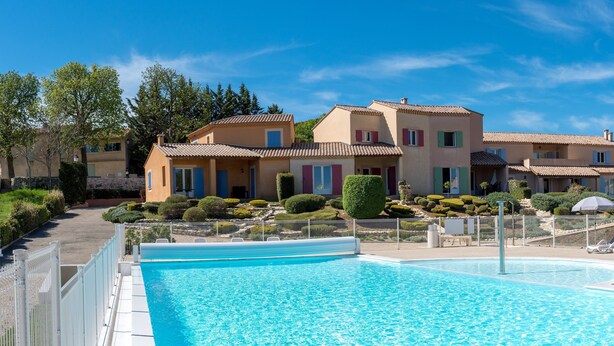 Un hotel con piscina, varias construcciones y jardines bien cuidados.