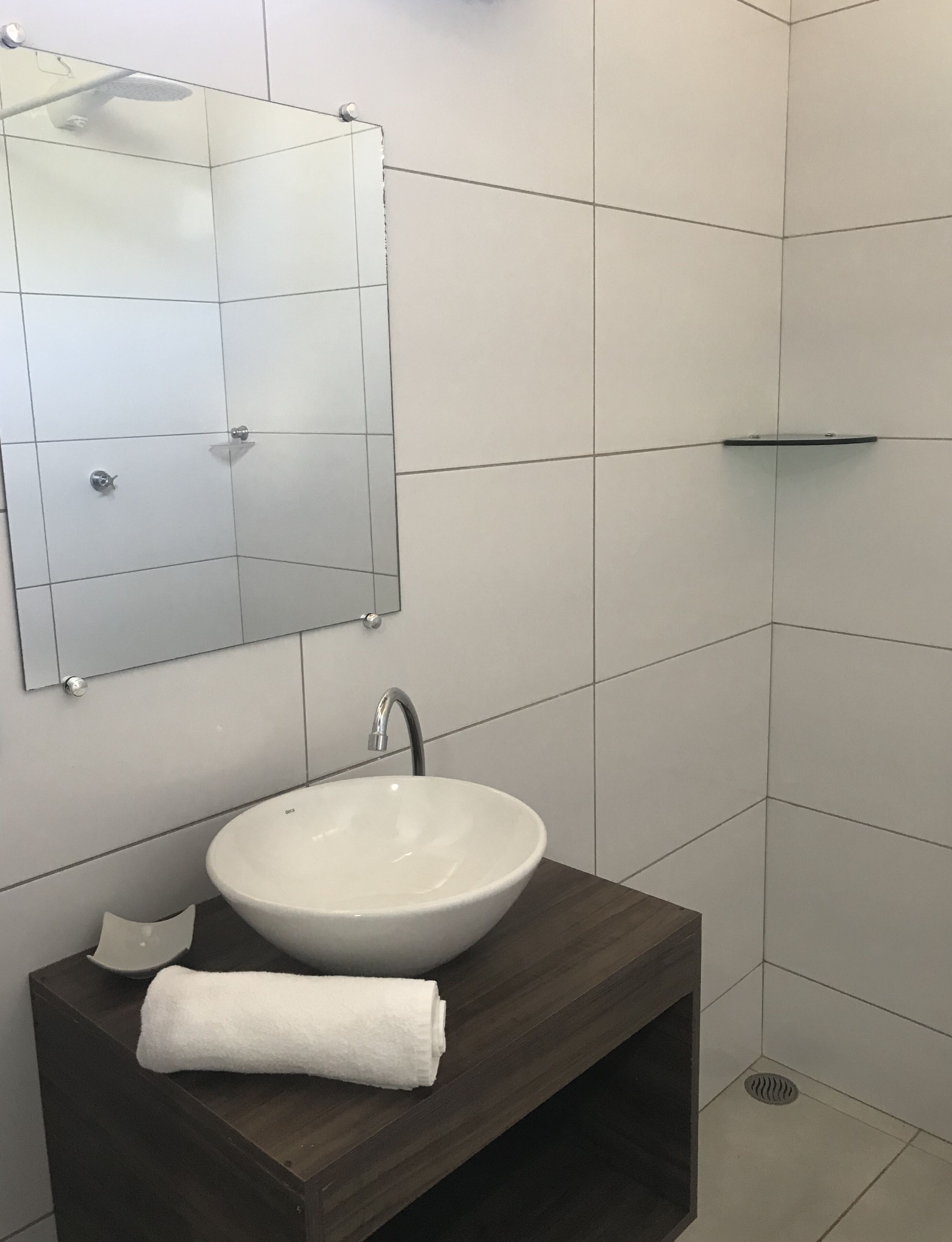 A bathroom with a white sink, a mirror, and a shower area.