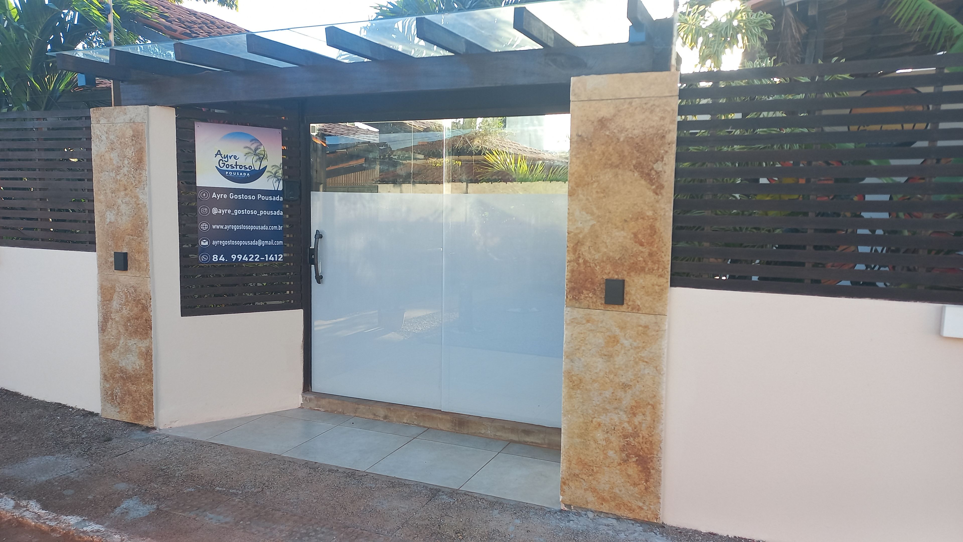 A gated entrance with a glass door, a contact number, and a business sign.