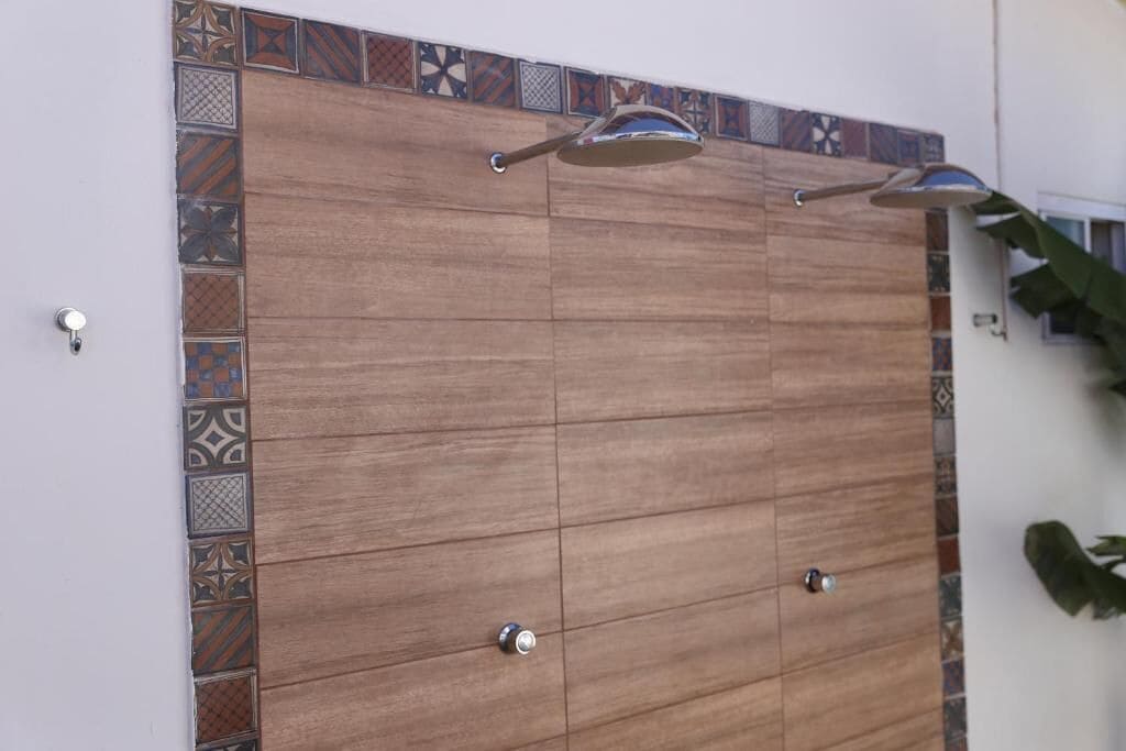 A shower enclosure with a tiled border and a wooden panel design.