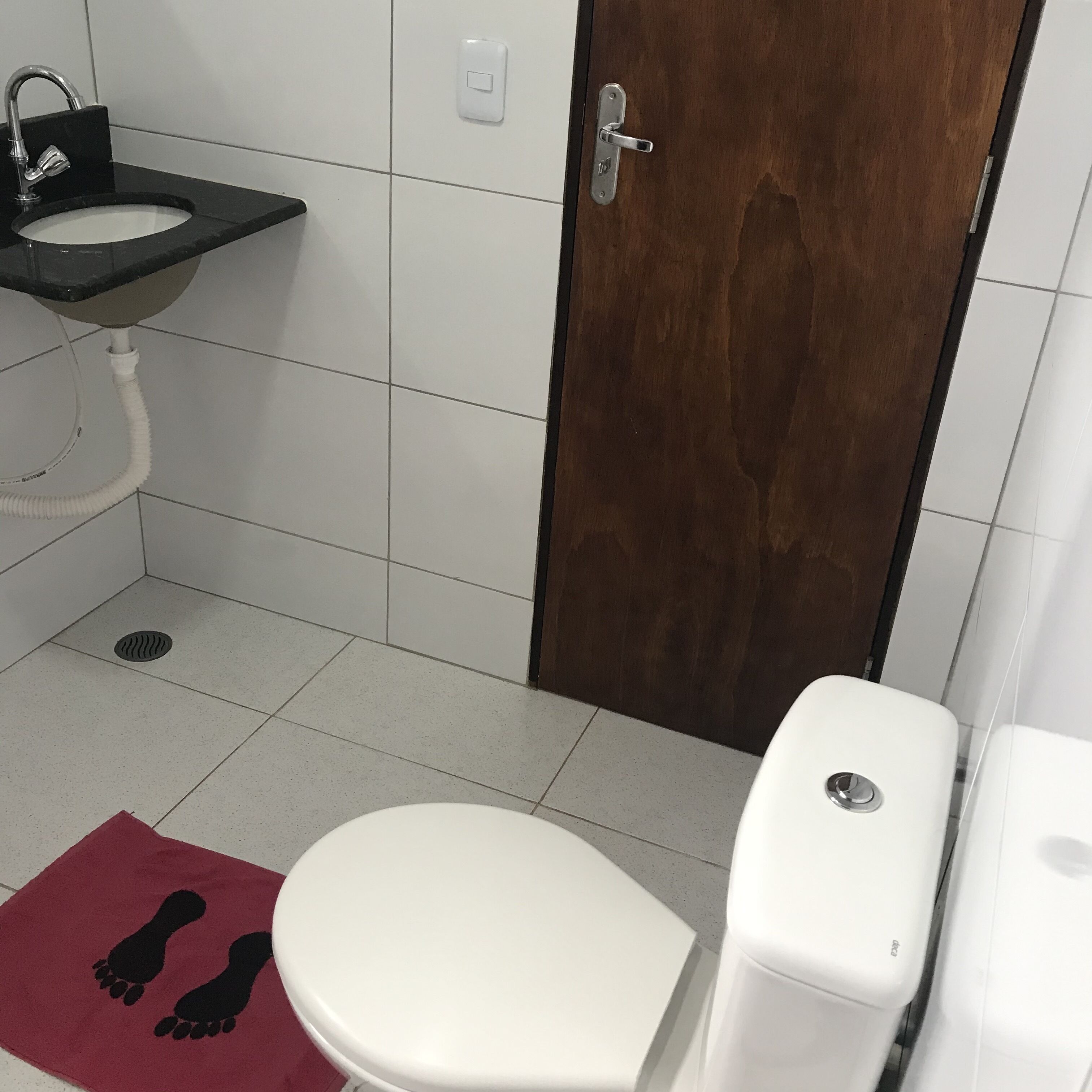 Une salle de bain avec des toilettes blanches, un lavabo et une douche.
