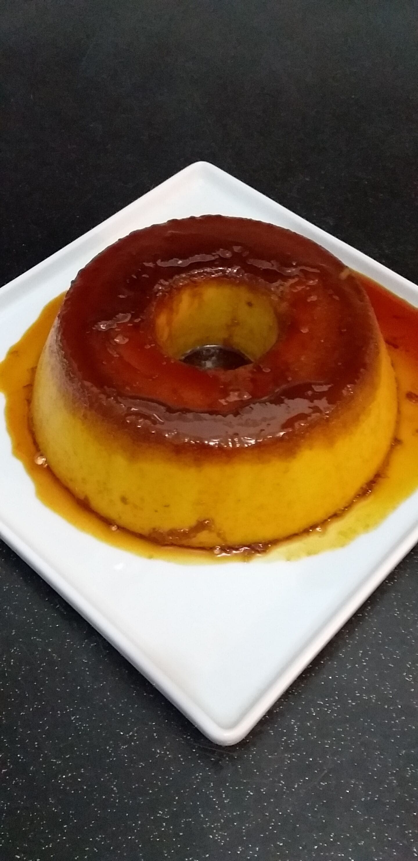 A caramel flan on a white plate.