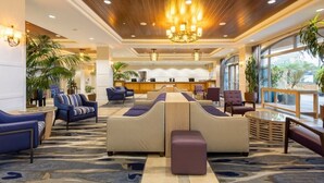 A hotel lobby with a reception desk, seating area, and large windows. - Club Wyndham Oceanside Pier Resort - 3 Bedroom (Oceanside)