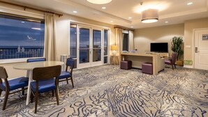 A hotel room with a balcony, a round table with chairs, a TV, and a desk with a lamp. - Club Wyndham Oceanside Pier Resort - 3 Bedroom (Oceanside)