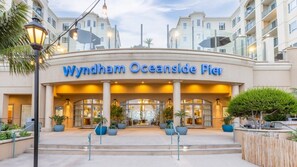 L’entrée de l’hôtel Wyndham Oceanside Pier se distingue par sa façade moderne, ses grandes fenêtres en verre et son espace d’accueil accueillant agrémenté de plantes en pot.
