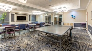 Une salle de conférence équipée d’une grande table, de chaises et d’un téléviseur à écran plat.