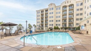 A hotel with a swimming pool, lounge chairs, and palm trees. - Club Wyndham Oceanside Pier Resort - 3 Bedroom (Oceanside)
