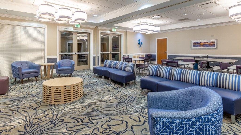 A hotel lobby with seating areas, a reception desk, and a patterned carpet.