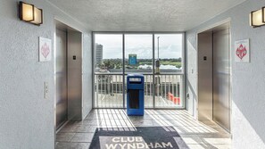 A hotel entrance with a Club Wyndham sign, a blue self-service kiosk, and a view of a golf course through the glass doors.