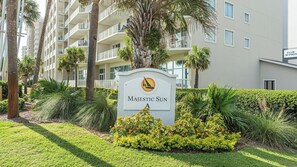 A sign for 'MAJESTIC SUN' with a palm tree and greenery in the foreground.