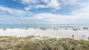 Ein Strand mit Menschen, Sonnenschirmen und blauem Himmel.
