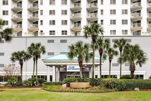 A multi-story hotel with balconies, palm trees, and a sign reading 'CLUB WYNDHAM'.