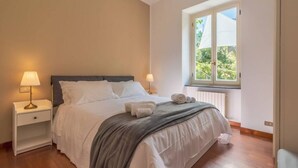A bedroom with a bed, bedside lamps, a window with a view, and a radiator. - CASA FLAMINIA - Panorama, Relaxation, and Parking (Ruta)