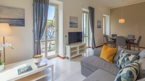 A modern living room with a sofa, TV, and dining area. - CASA FLAMINIA - Panorama, Relaxation, and Parking (Ruta)