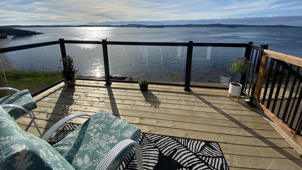 Eine Terrasse mit Gartenmöbeln mit Blick auf ein Gewässer.