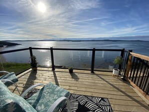 Eine Terrasse mit Gartenmöbeln mit Blick auf ein Gewässer.
