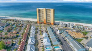 A coastal hotel with a central building, multiple parking lots, and a beach view. - Three Minutes to White Sand Beach! (Panama City Beach)