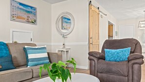A living room with a beige sofa, a brown leather chair, a white coffee table, and a potted plant. - Three Minutes to White Sand Beach! (Panama City Beach)