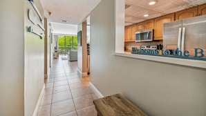 A modern kitchen with a stainless steel refrigerator, wooden cabinets, and a microwave. - Waterfront views - steps from the Beach! (Indian Shores)