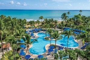 Relax by the resort's large pool surrounded by palm trees and lounge chairs, with the ocean just steps away.