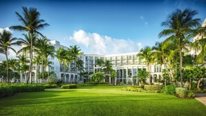 A hotel with a central courtyard, palm trees, and a modern building facade. - Rio Mar Puerto Rico | Caribbean Family Getaway | Pool & Beach | 3BR Sleeps 10 (Rio Grande)