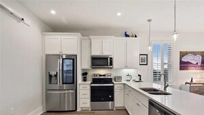 A modern kitchen with white cabinets, stainless steel appliances, and a large island with a sink. - Moorings 31 - Sunset Spectacular<br>The Moorings at Jekyll Harbor Marina (Jekyll Island)
