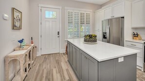 A modern kitchen with a central island, white cabinetry, and a stainless steel refrigerator. - The Moorings 43 Relax in Luxury - Pet Friendly (Jekyll Island)