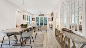 A spacious dining area with a long table, chairs, and a chandelier. - The Moorings 43 Relax in Luxury - Pet Friendly (Jekyll Island)