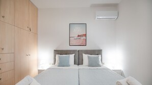 A double bed with two pillows, a wooden wardrobe, a framed picture on the wall, and a rolled towel on the bed. - Villa Telio: Sunny pool, A/C, WiFi, BBQ (Sgompou)