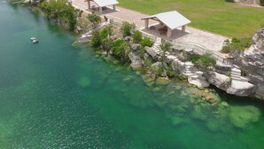 A lakeside property with clear water, picnic areas, and a boat dock. - The River Lodge (Uvalde)
