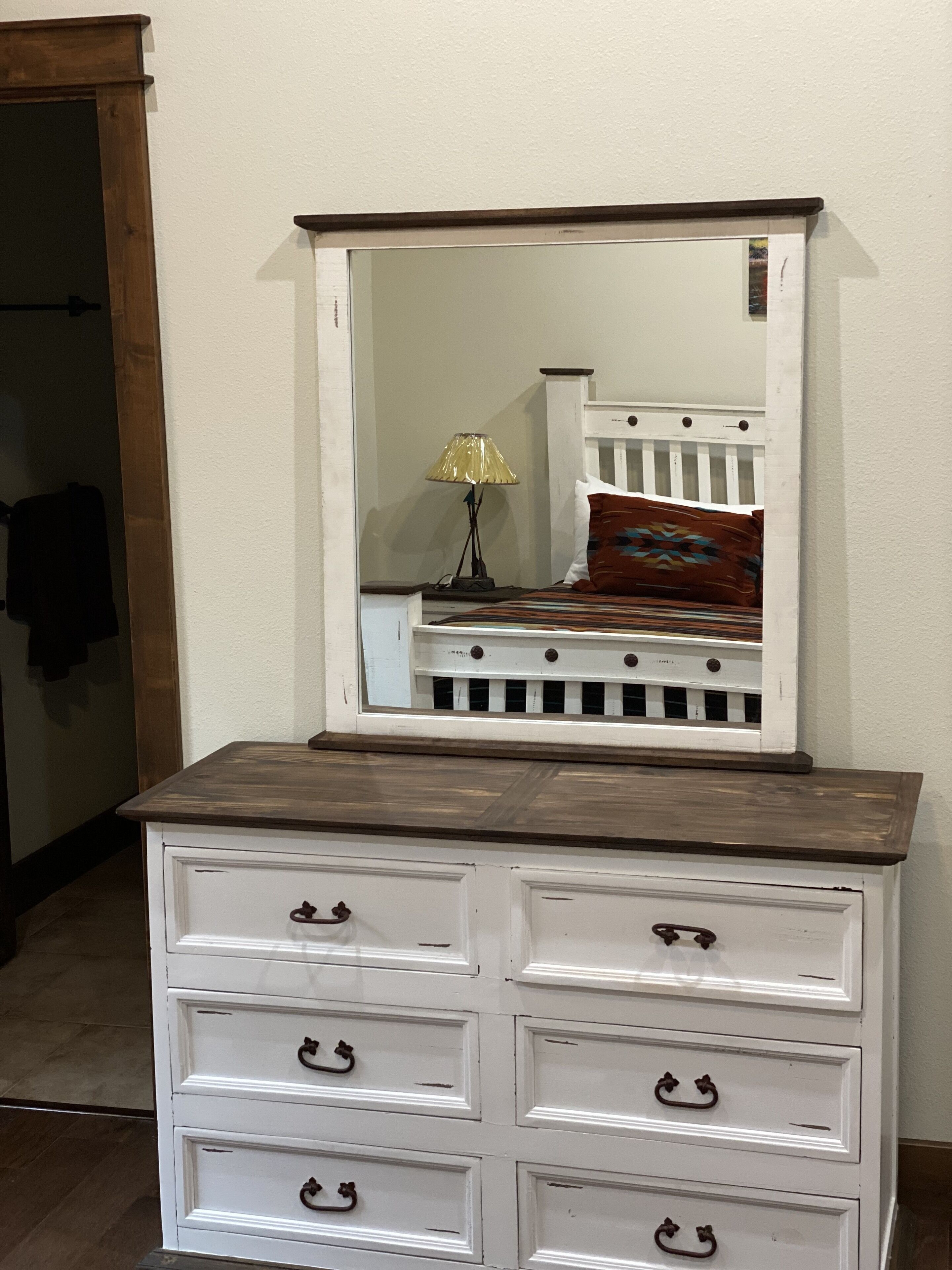 A white dresser with four drawers and a mirror above it.