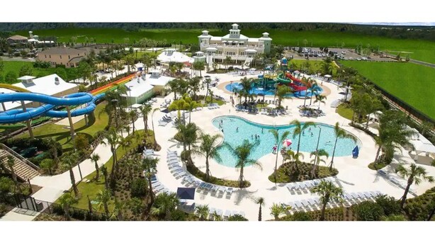 Un resort con una piscina grande, toboganes acuáticos y un edificio central.