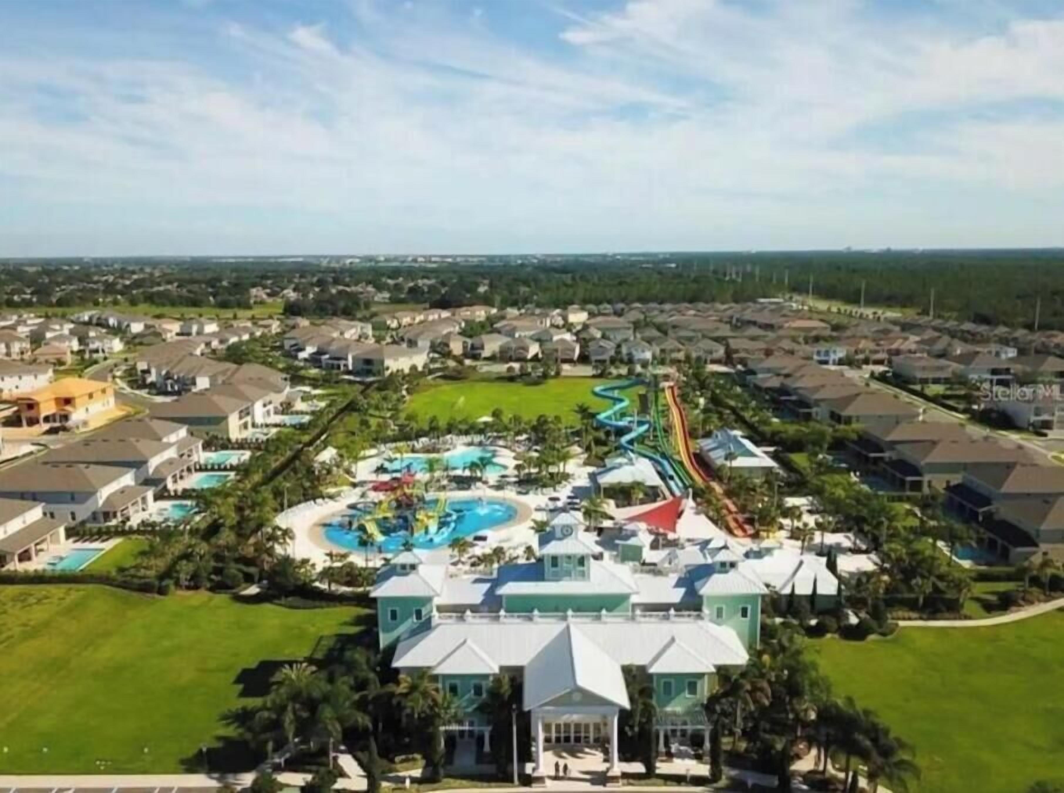 Vista aérea de um bairro residencial com um prédio grande, piscina e toboágua.