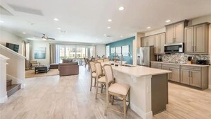 Una cocina amplia con una isla grande, electrodomésticos modernos y una zona de comedor con taburetes de bar.
