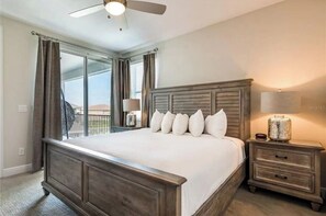 Relax in a spacious bedroom with a large bed, nightstand, and window with curtains.