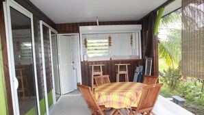 Un espace patio avec une table et des chaises, une porte-fenêtre coulissante et une vue sur le jardin.