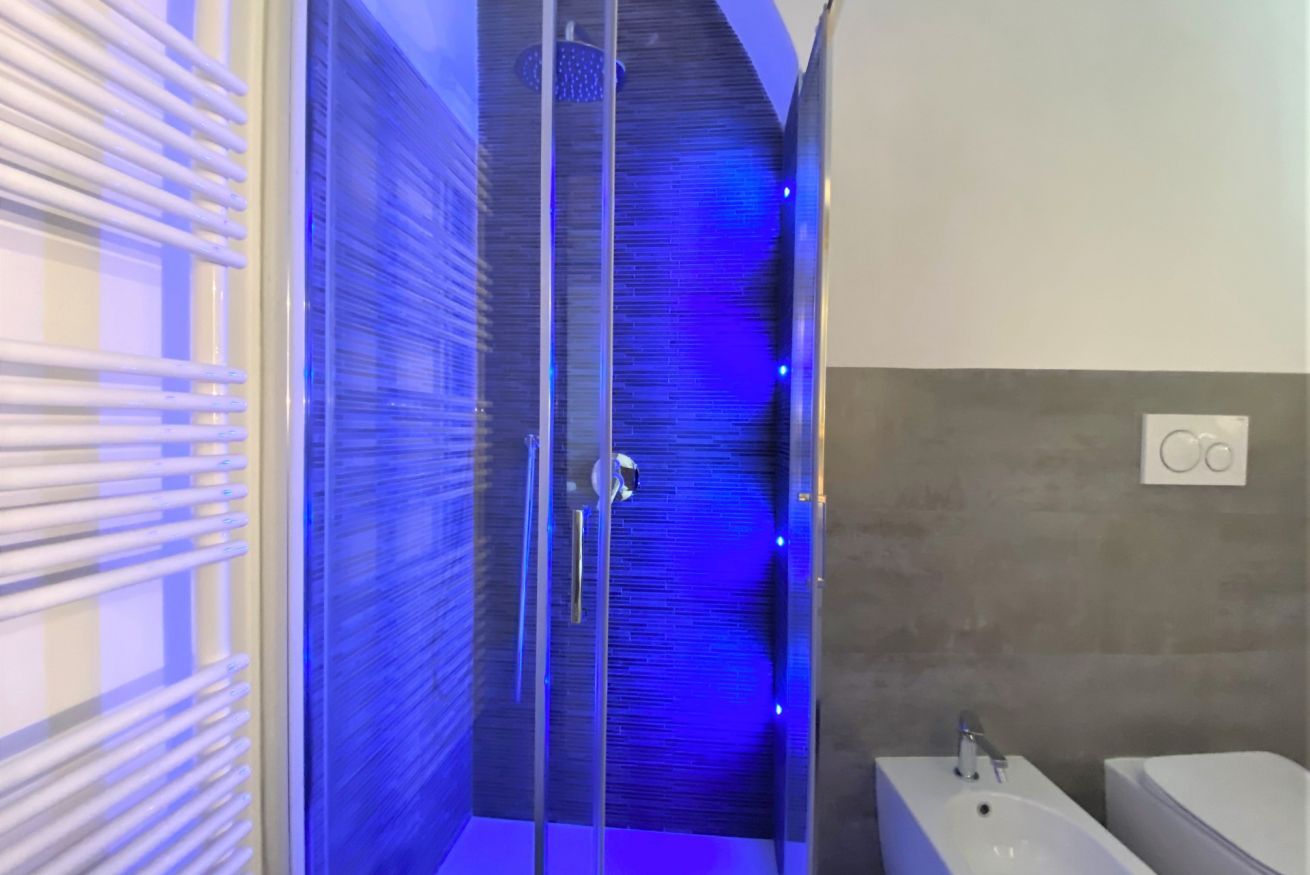A modern bathroom with a glass shower enclosure, a white sink, and a toilet.