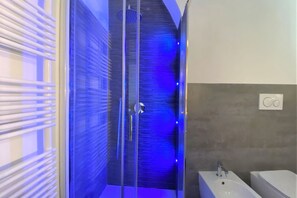 A modern bathroom with a glass shower enclosure, a white sink, and a toilet.
